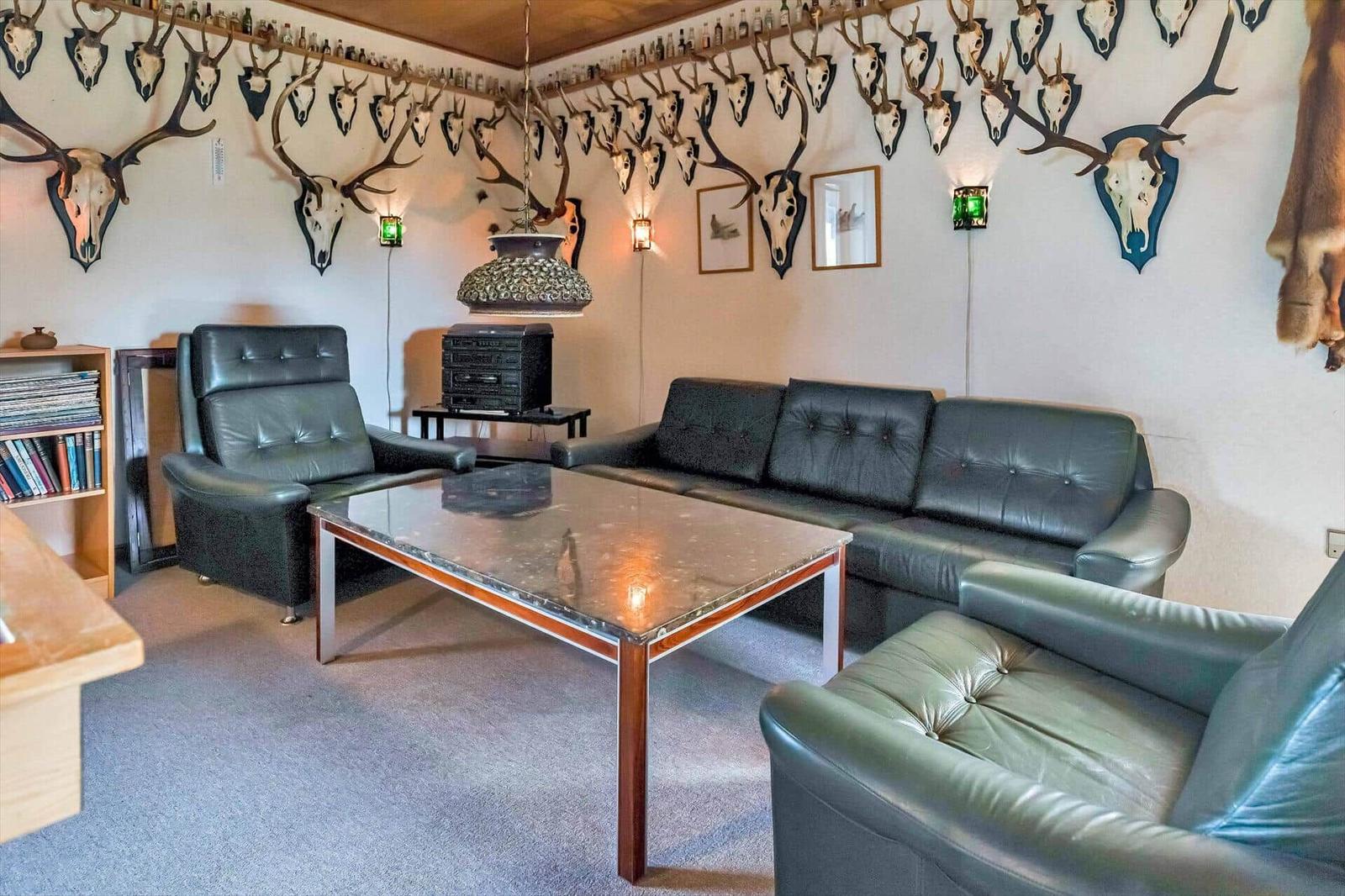 Living room with leather sofa, chairs, and table. Wall decor with deer antlers and skulls.
