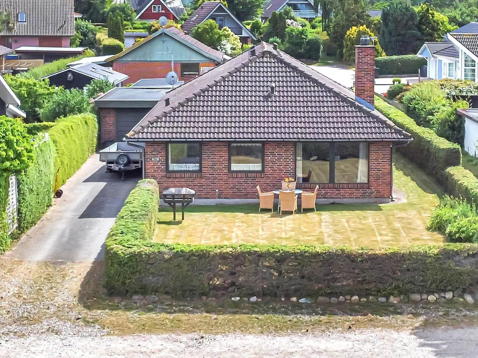 A house with stone wall, grill, and seating area on the terrace.