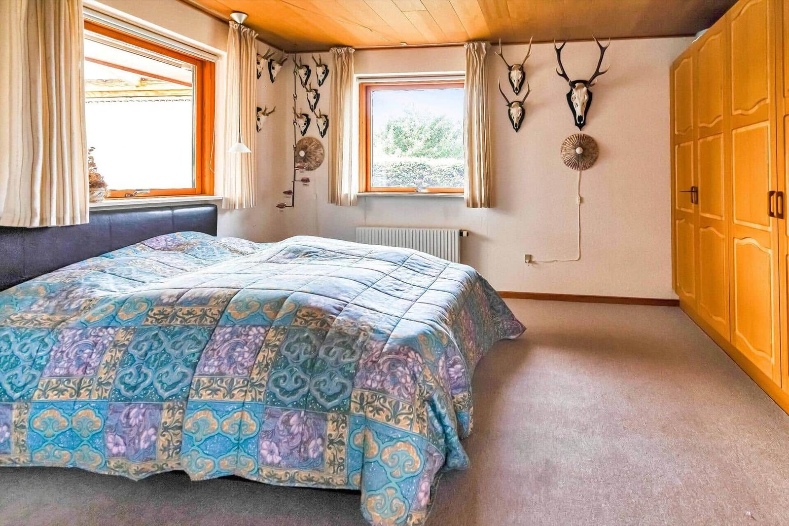 Bedroom with bed, windows, and wall decoration.
