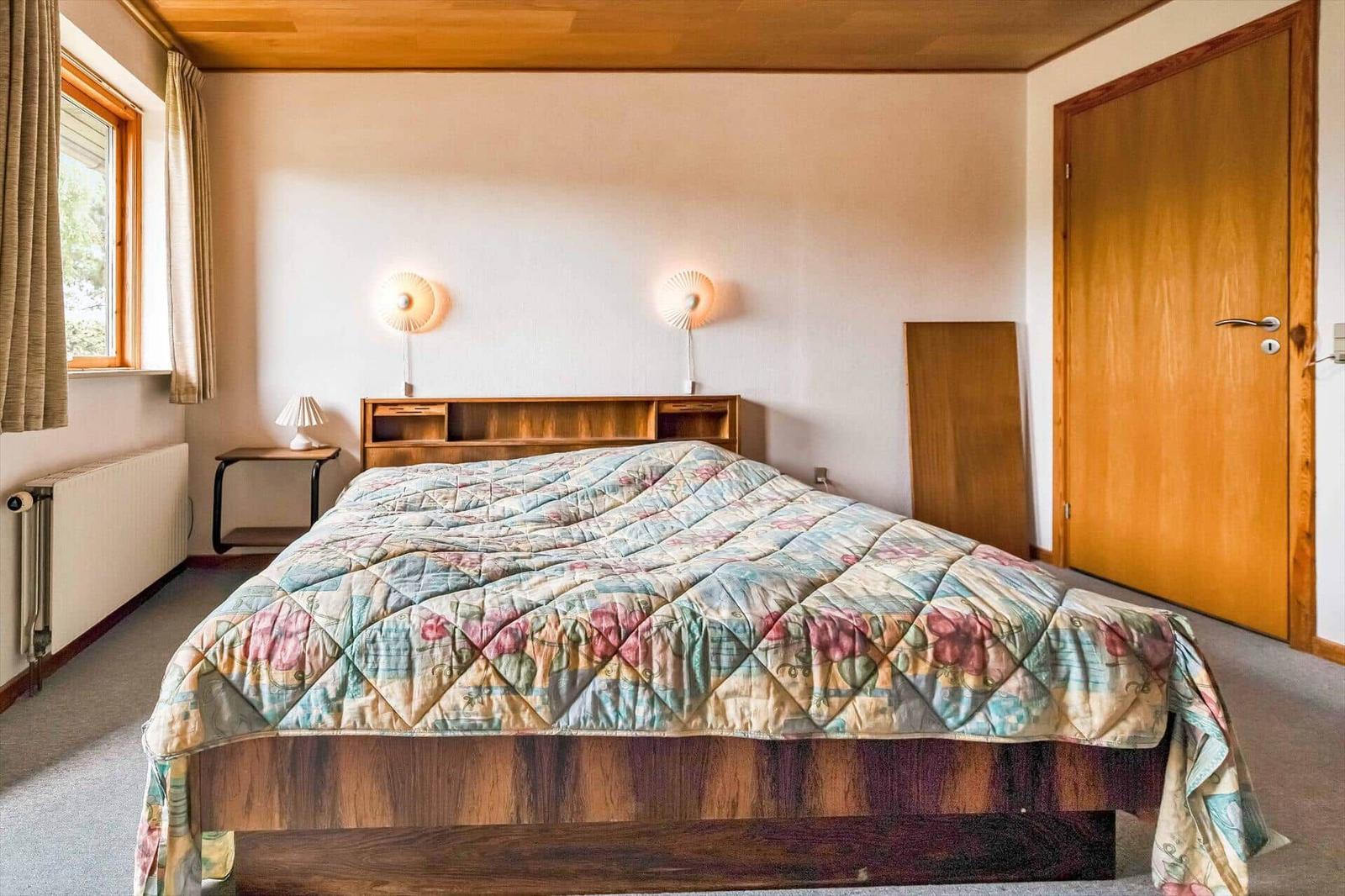 Bedroom with bed, nightstand, wall lamps, and window