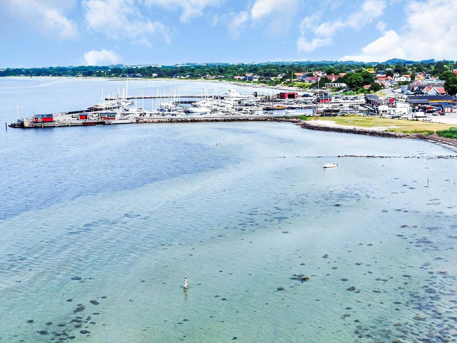 Harbor with boats and clear water. A person swims in the foreground.