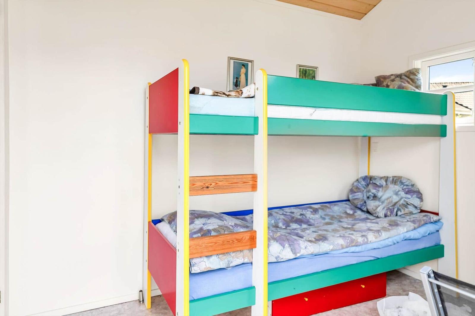 Room with climbing wall and bunk bed with colorful mattresses.