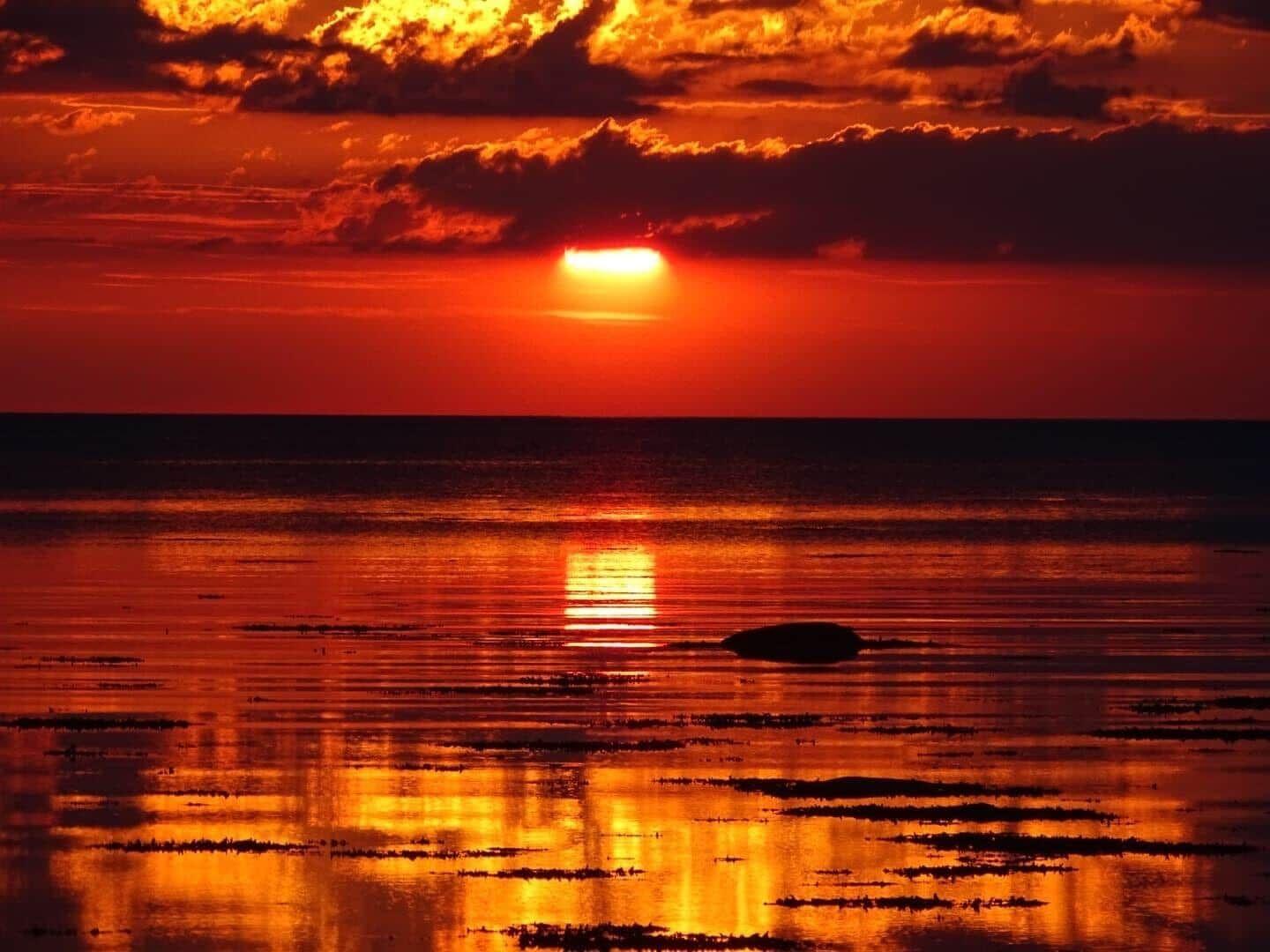 Sunset over the sea with orange sky and reflection on the water surface.