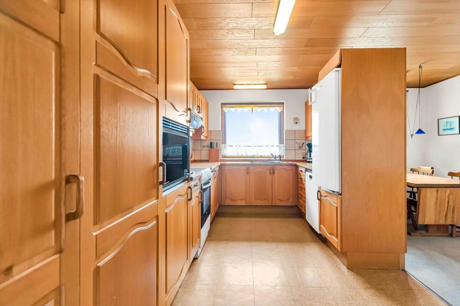 Kitchen with wooden cabinets, refrigerator, and window