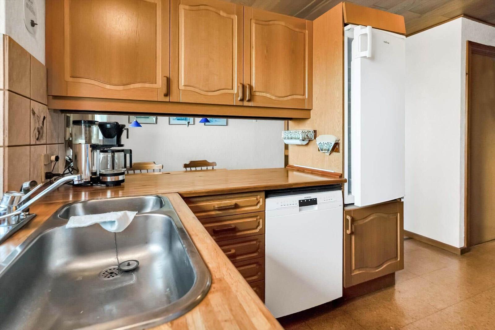 Kitchen with wooden cabinets, sink, refrigerator, and dishwasher.