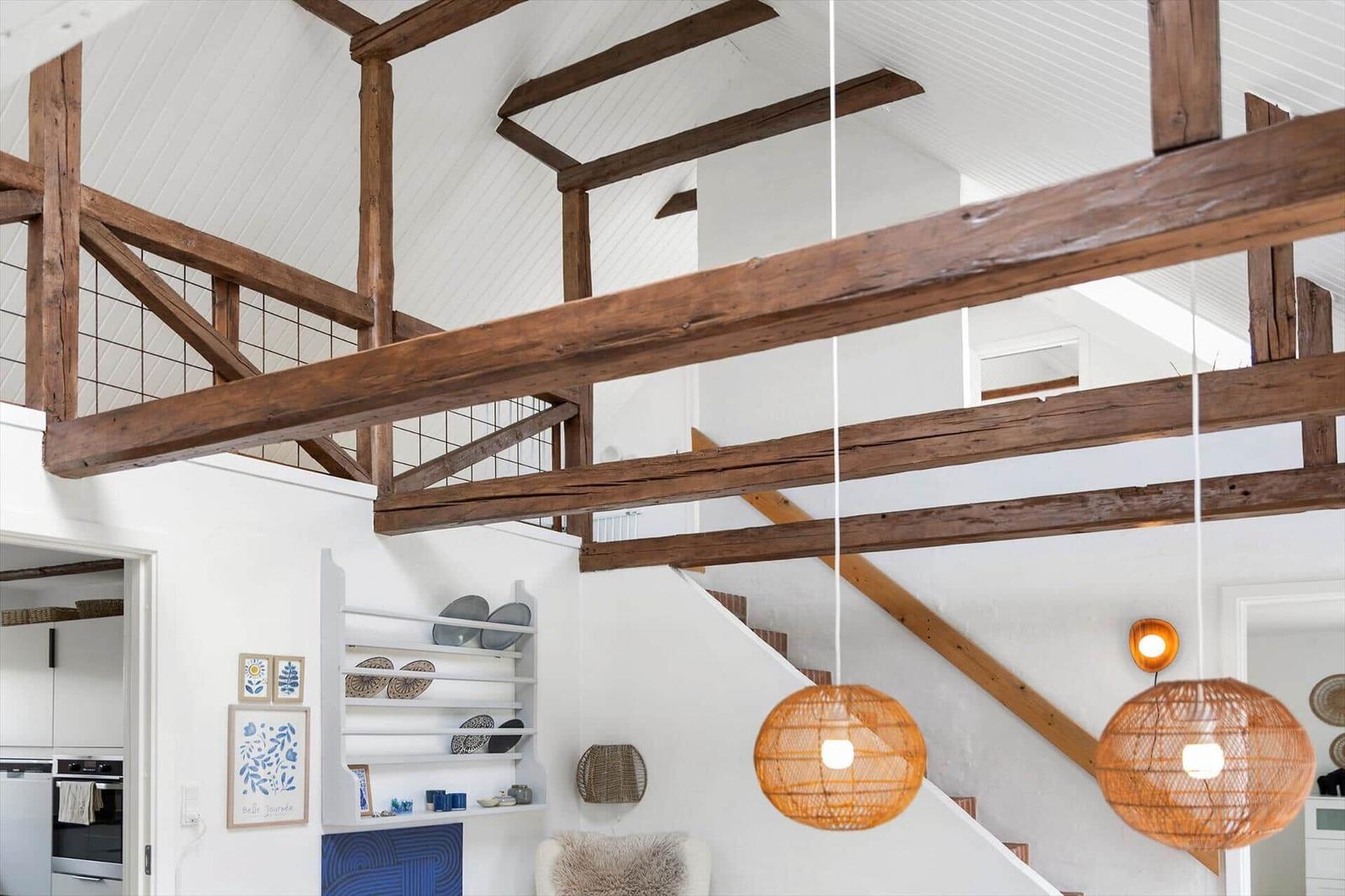 Raum mit Holzbalken, Treppe und hängenden Lampen