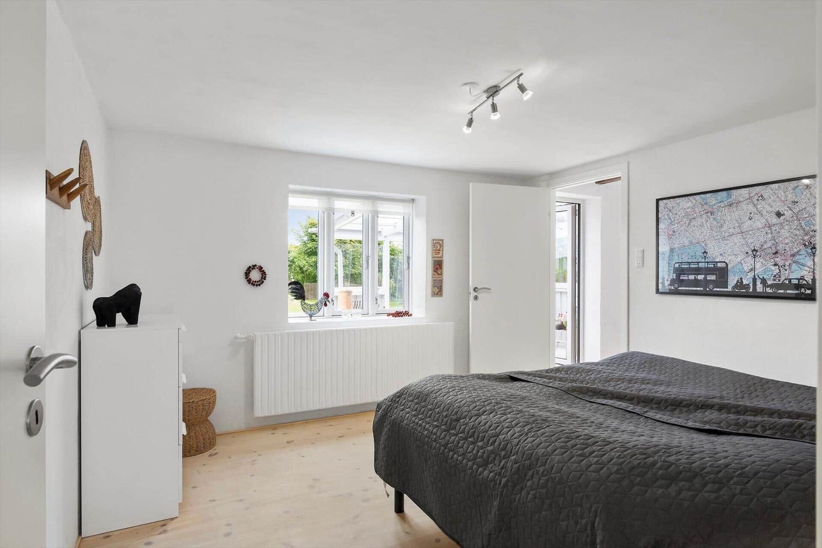 Schlafzimmer mit Bett, Fenster und Wandbild.