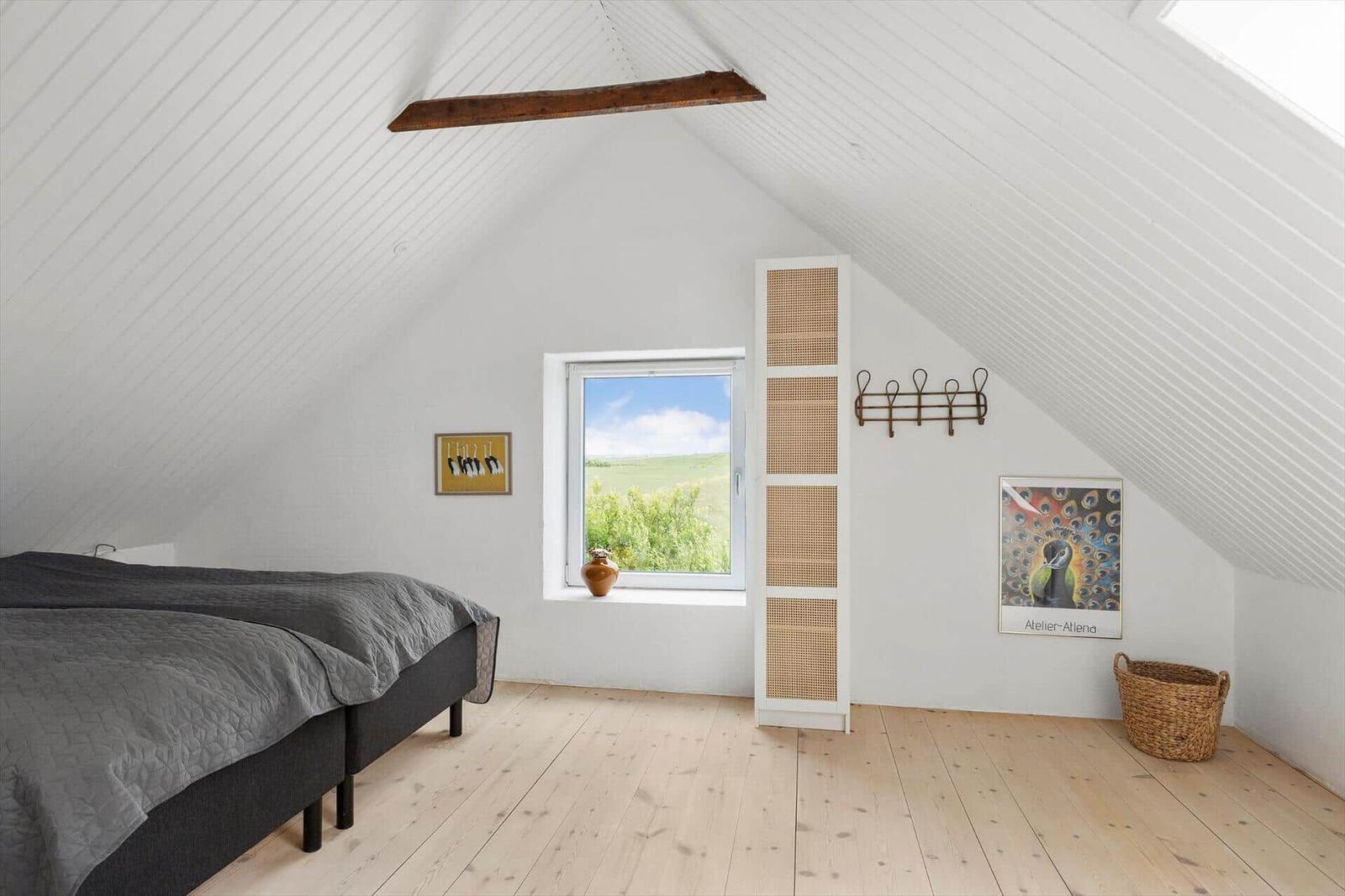 Schlafzimmer mit Dachschräge, Fenster und Holzboden