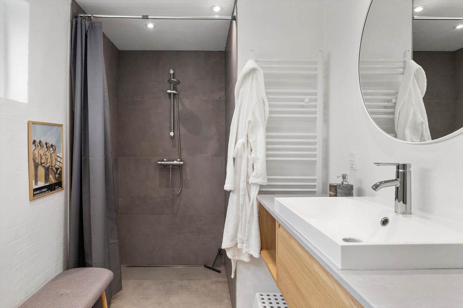 Badezimmer mit Dusche, Waschbecken und Bademantel.