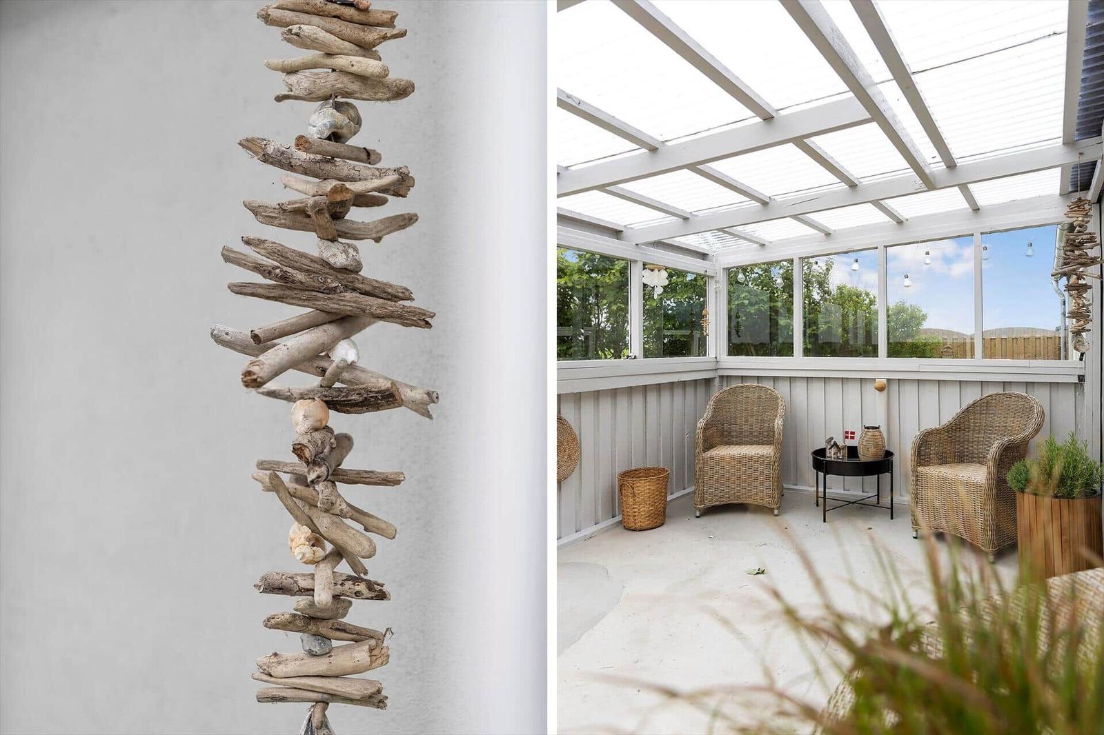 Terrasse mit zwei Strohstühlen, Glasdach und Druckholzdekoration an der Wand.