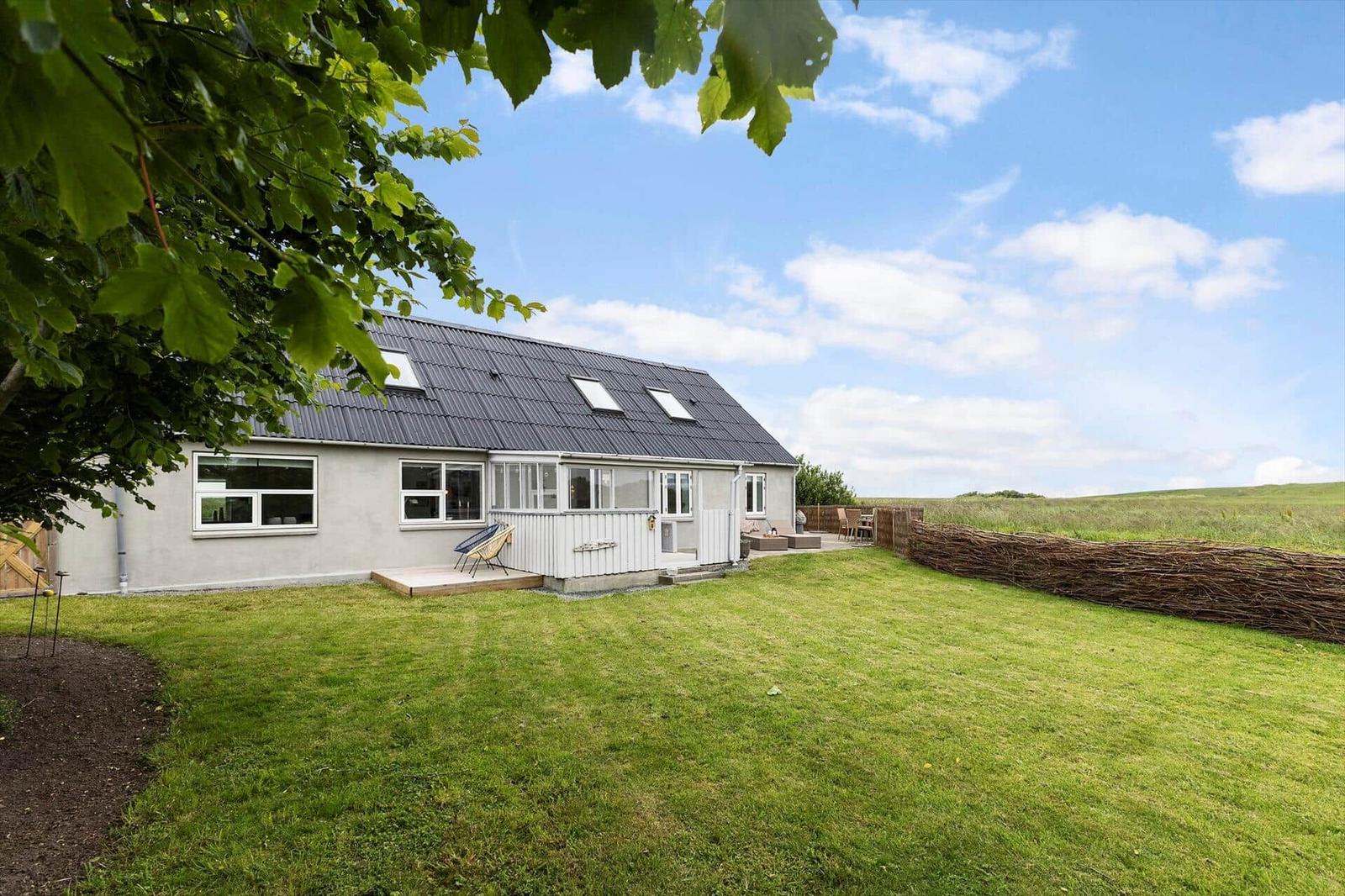 Ein Haus mit Garten und Terrasse unter blauem Himmel.