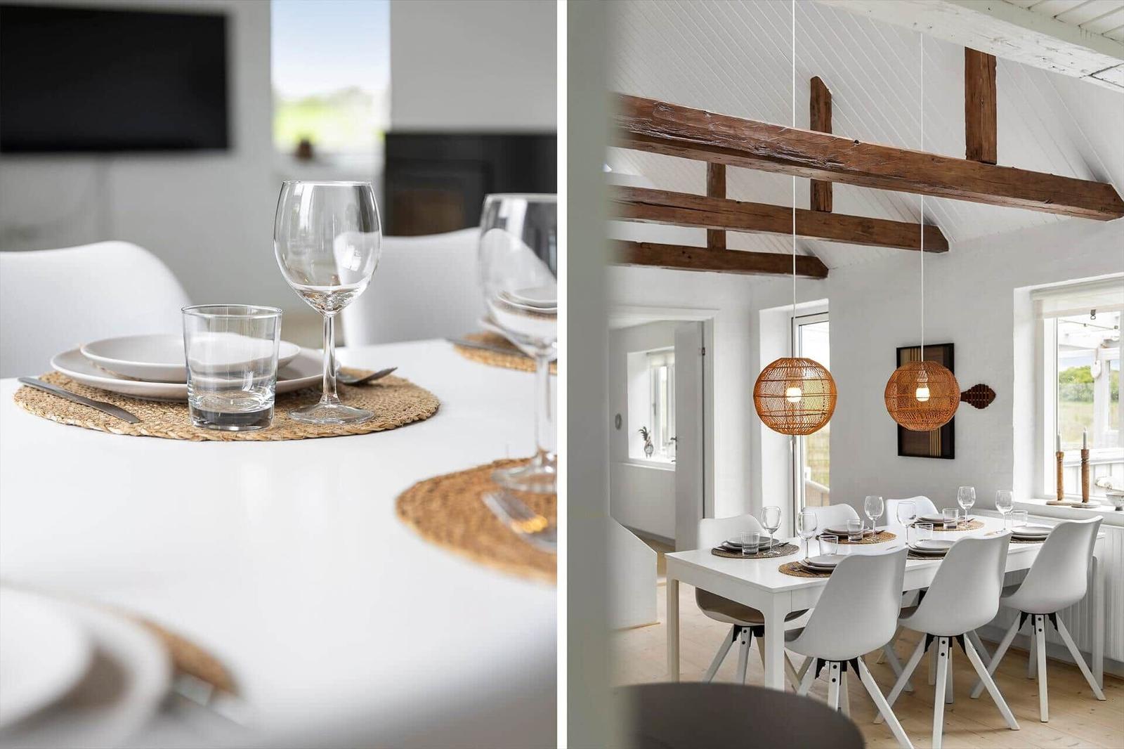 Esszimmer mit weißem Tisch, weißen Stühlen und Holzbalken an der Decke.