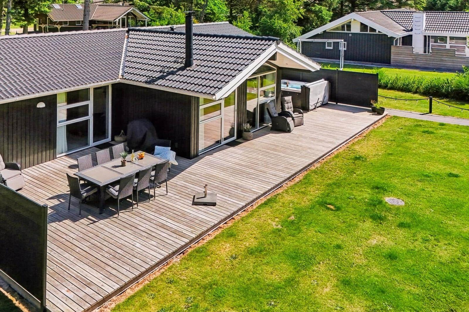 Haus mit großem Holzterrasse, Grillplatz und Garten. Pool und Sitzgelegenheiten sind vorhanden.