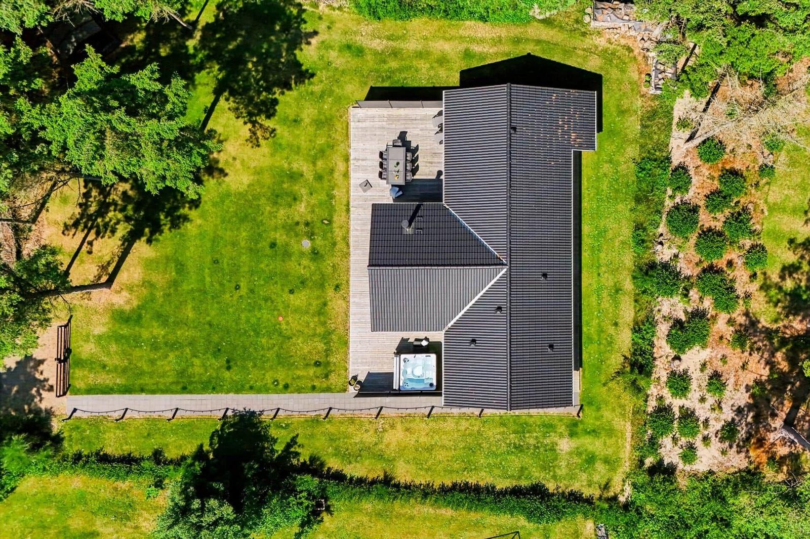 Modernes Haus mit Terrasse, Whirlpool und großem Garten in grüner Umgebung.