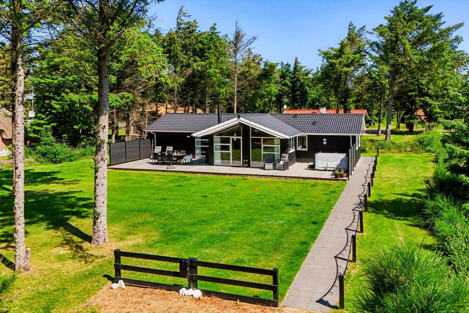 Moderne Villa mit großem Garten und Terrasse. Umgeben von Bäumen und grünem Rasen.