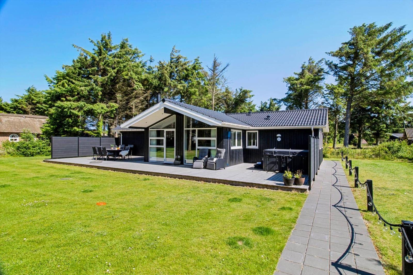 Moderne Villa mit großem Garten, Terrasse und Grillplatz. Umgeben von Bäumen.