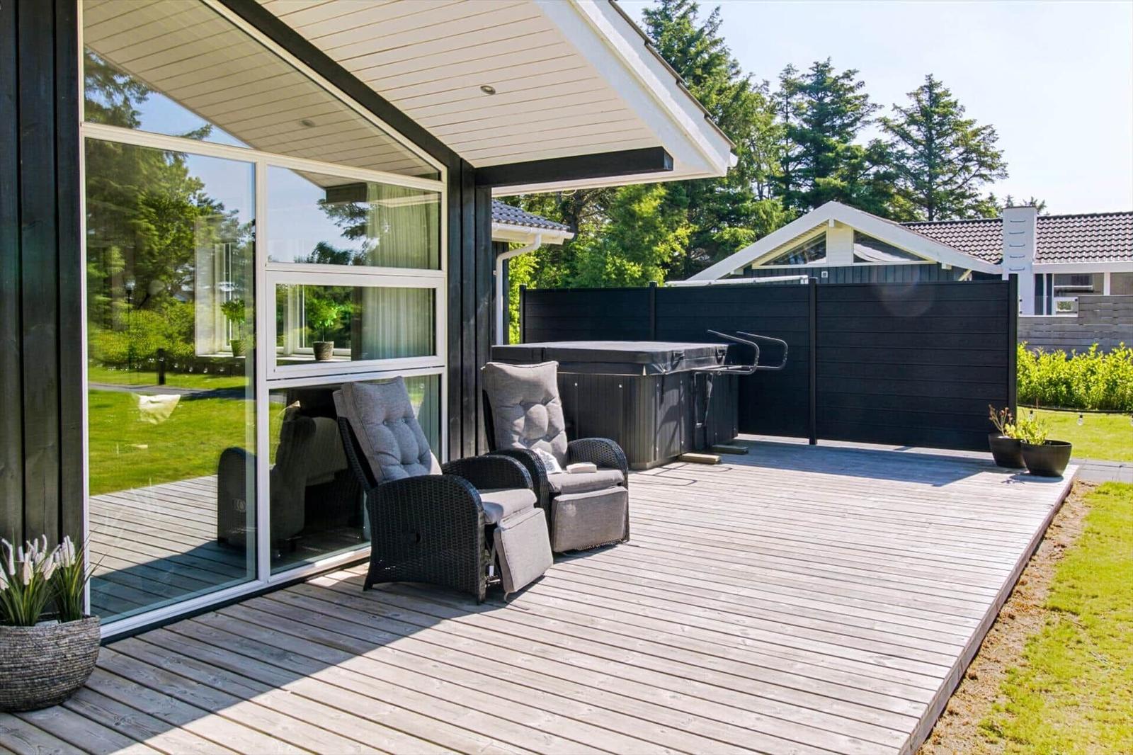 Terrasse mit Liegegelegenheit und Whirlpool. Holzdecke, Sicht auf Garten und Nachbarhaus.