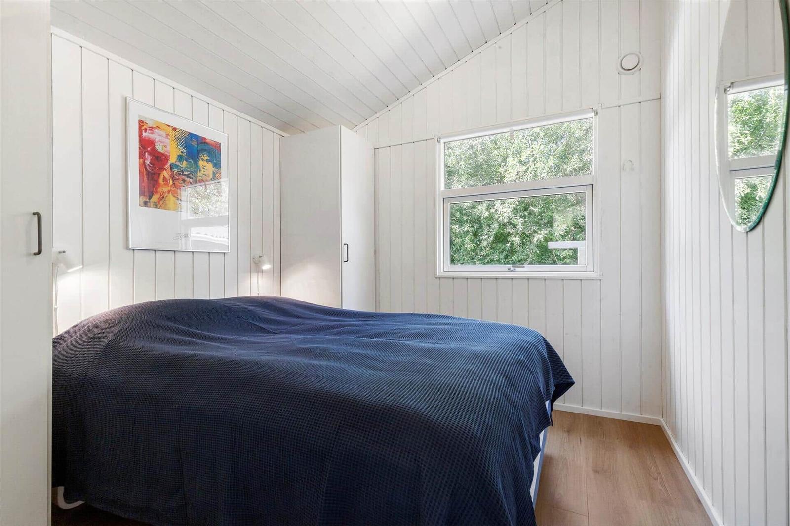 Schlafzimmer mit Bett, Fenster und Wandbild.