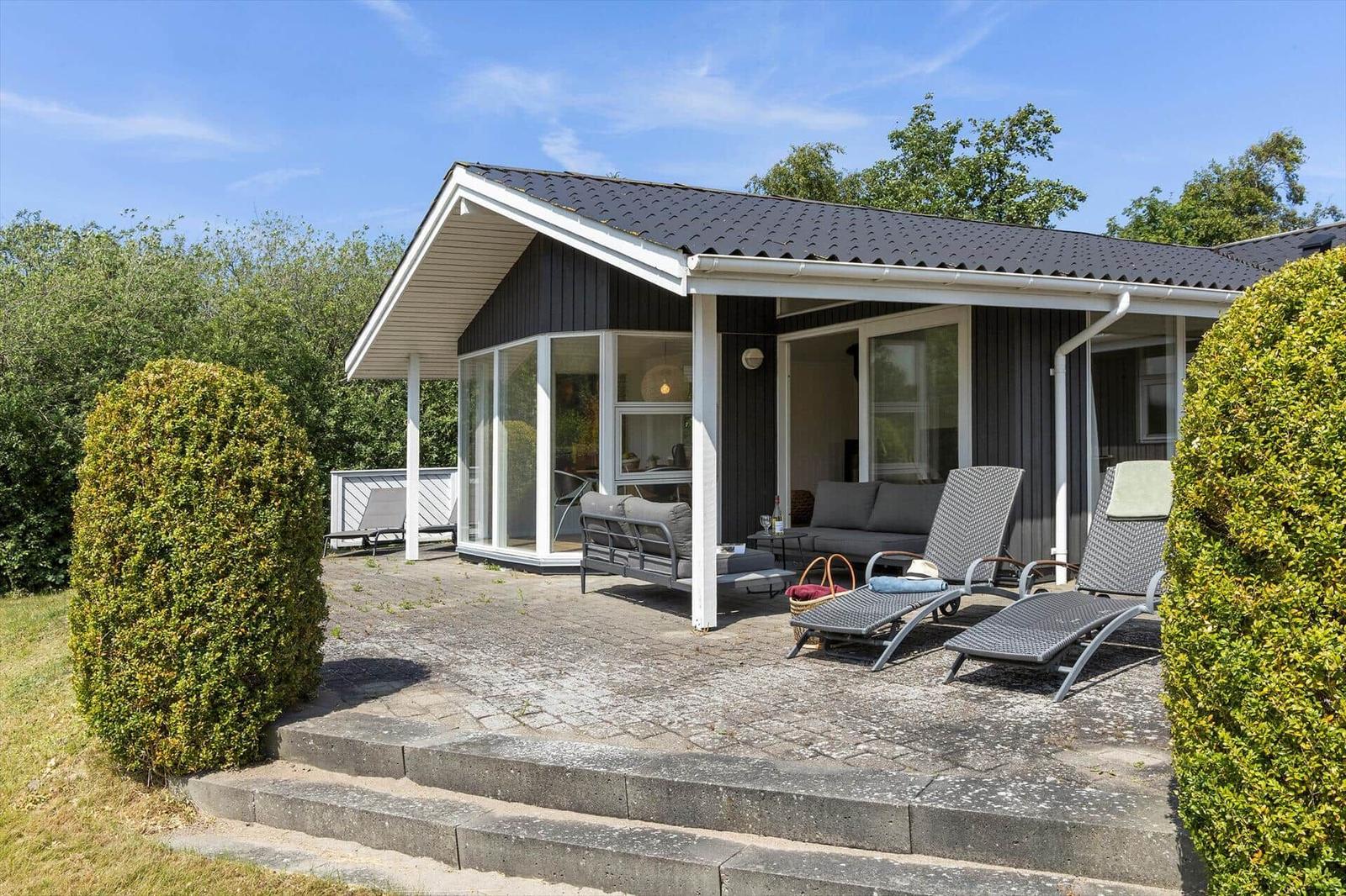 Moderne Villa mit Terrasse, Sonnenliegen und grüner Umgebung.