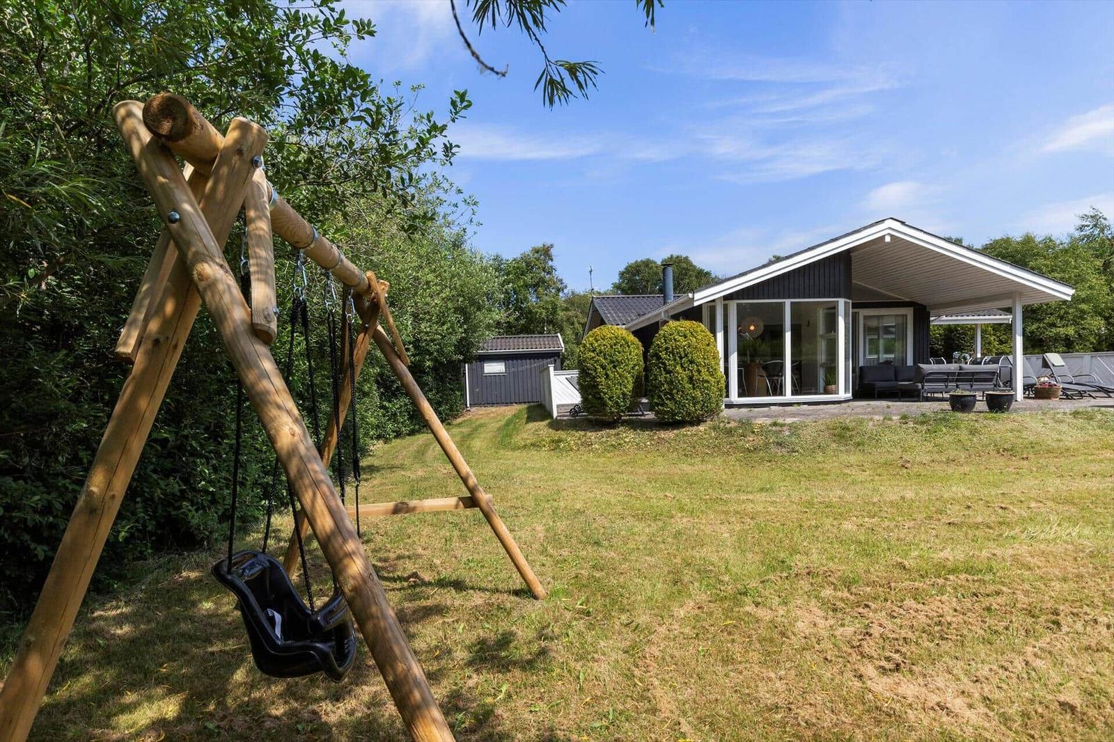 Haus mit Terrasse, Garten und Schaukel im Freien.