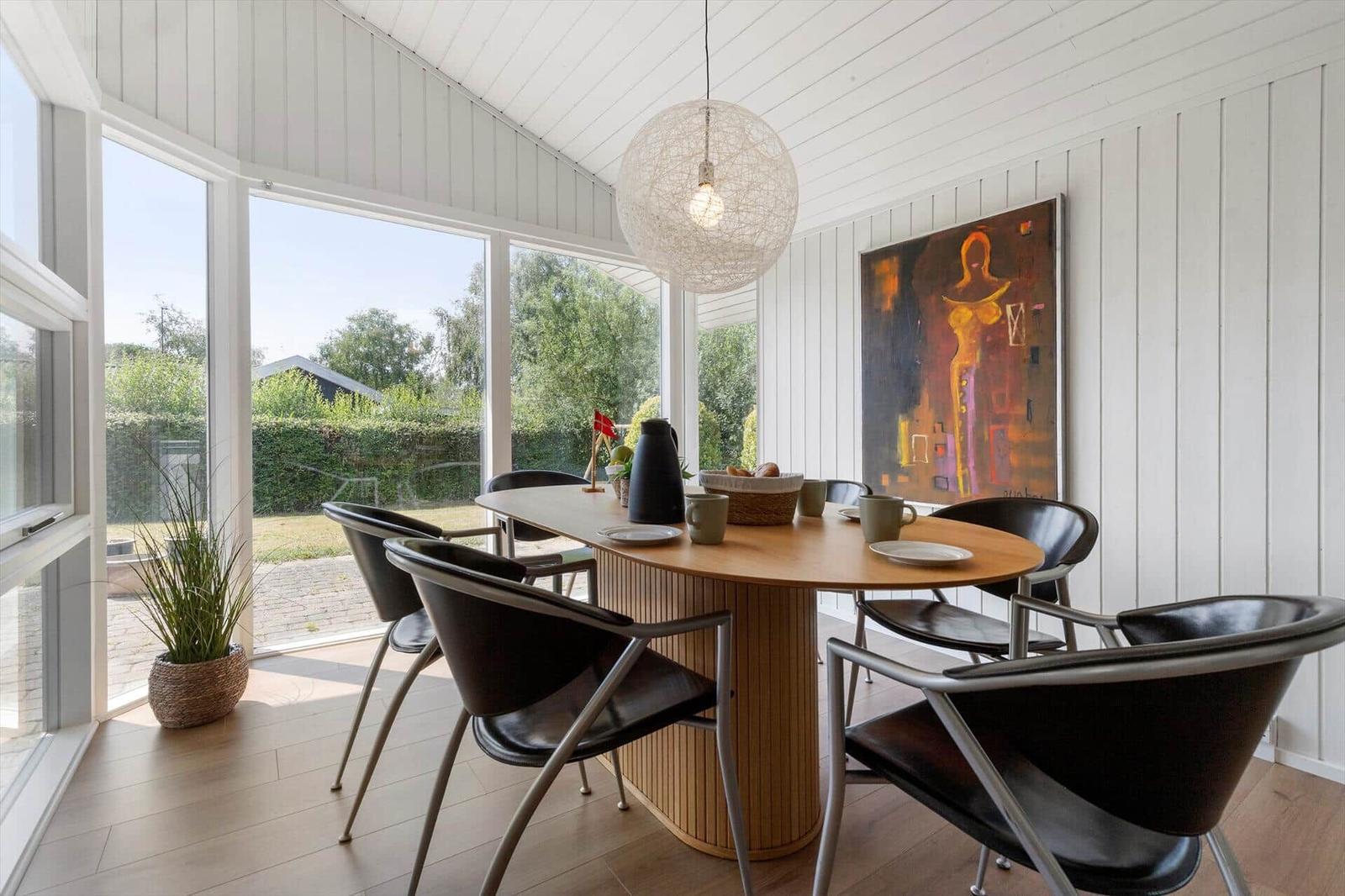 Esszimmer mit Holztisch, schwarzen Stühlen und großem Fensterblick auf Garten