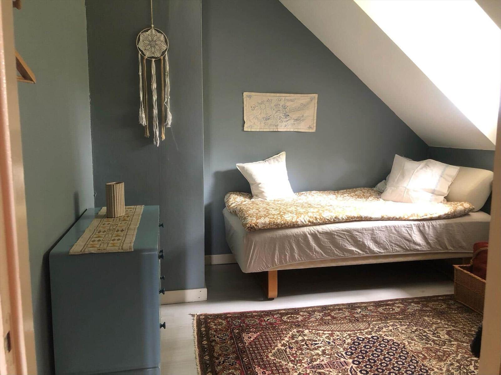 Schlafzimmer mit Dachschrägen, Bett, Schrank und Teppich