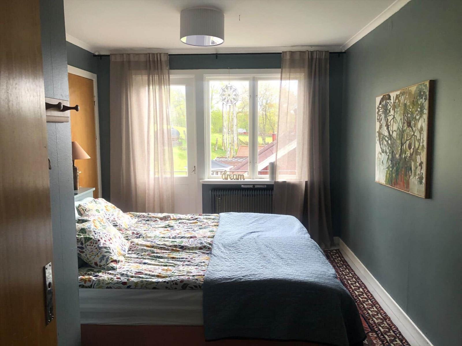 Schlafzimmer mit Bett, Fenster und Wandbild.
