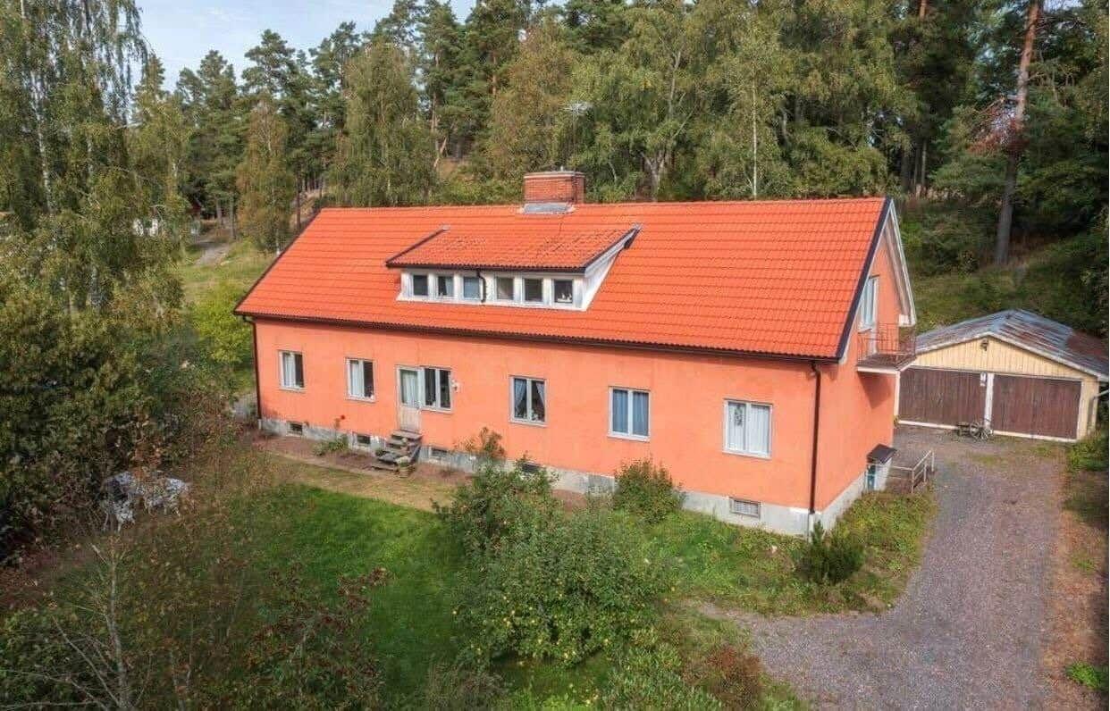 Ein orangefarbenes Haus mit rotem Dach steht inmitten von Bäumen.