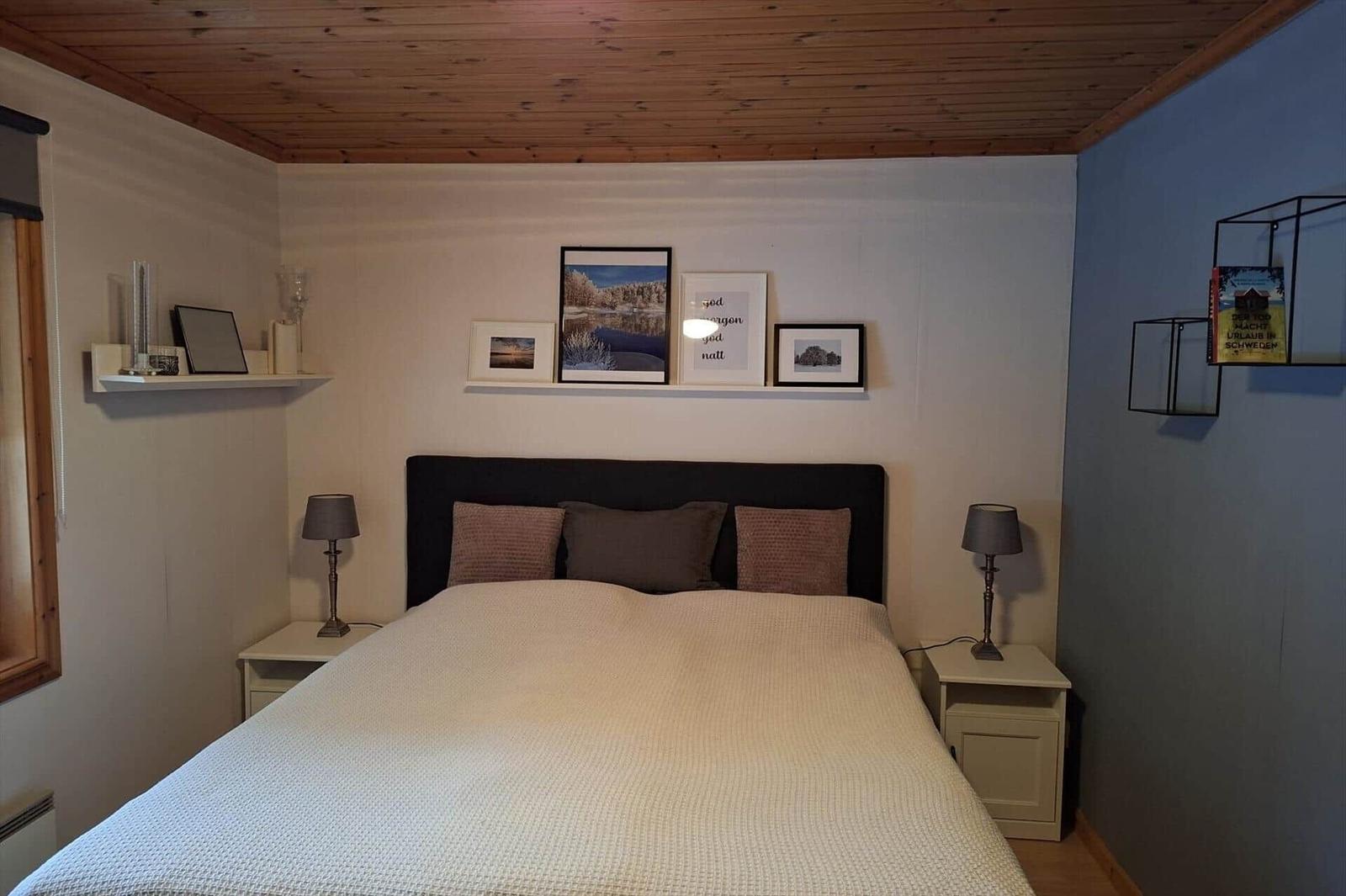 Schlafzimmer mit Doppelbett, Nachttischen und Wanddekoration.
