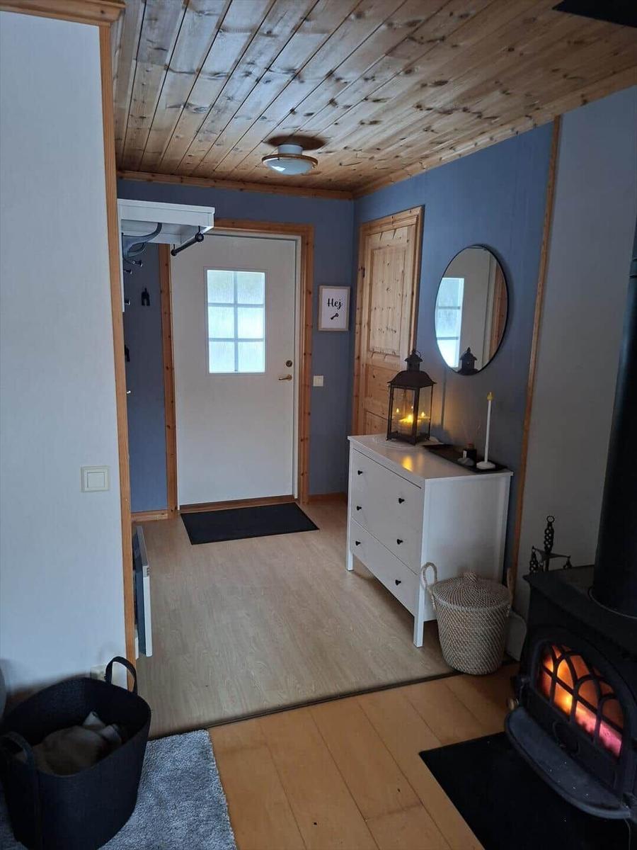 Eingangsbereich mit Holzdecke, Schrank und Kaminofen mit brennendem Feuer.
