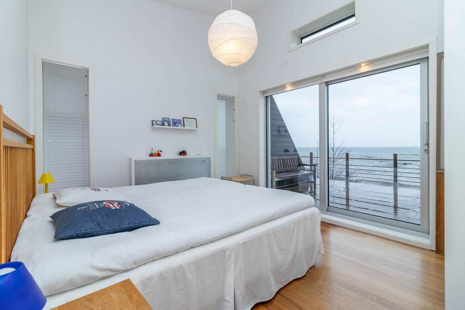 Schlafzimmer mit Blick aufs Meer und Holzboden.