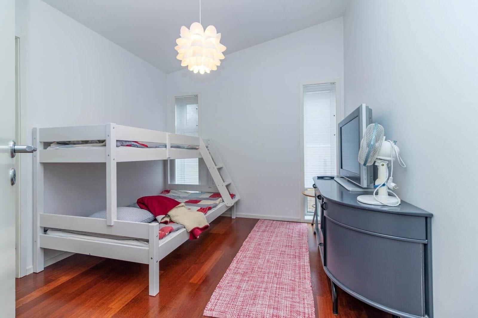 Zimmer mit Doppelbett, Fernseher und Lüfter auf Schrank.