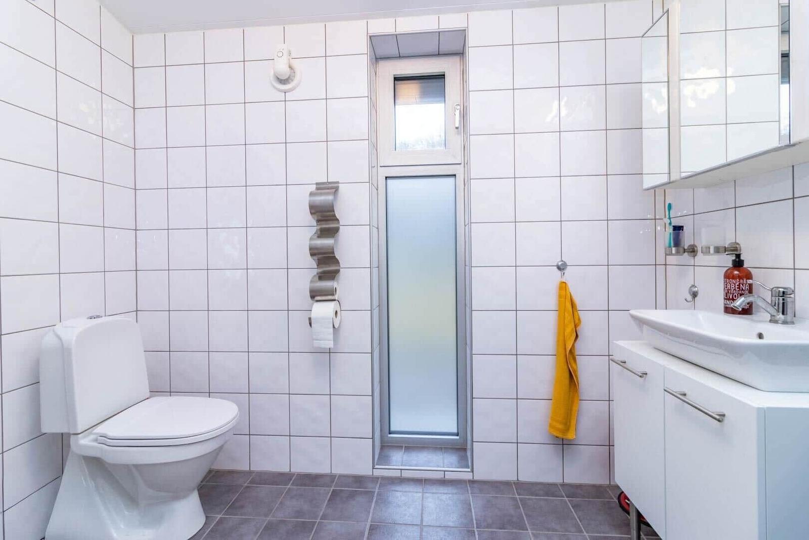 Badezimmer mit Toilette, Waschbecken und Dusche mit Glaswand.