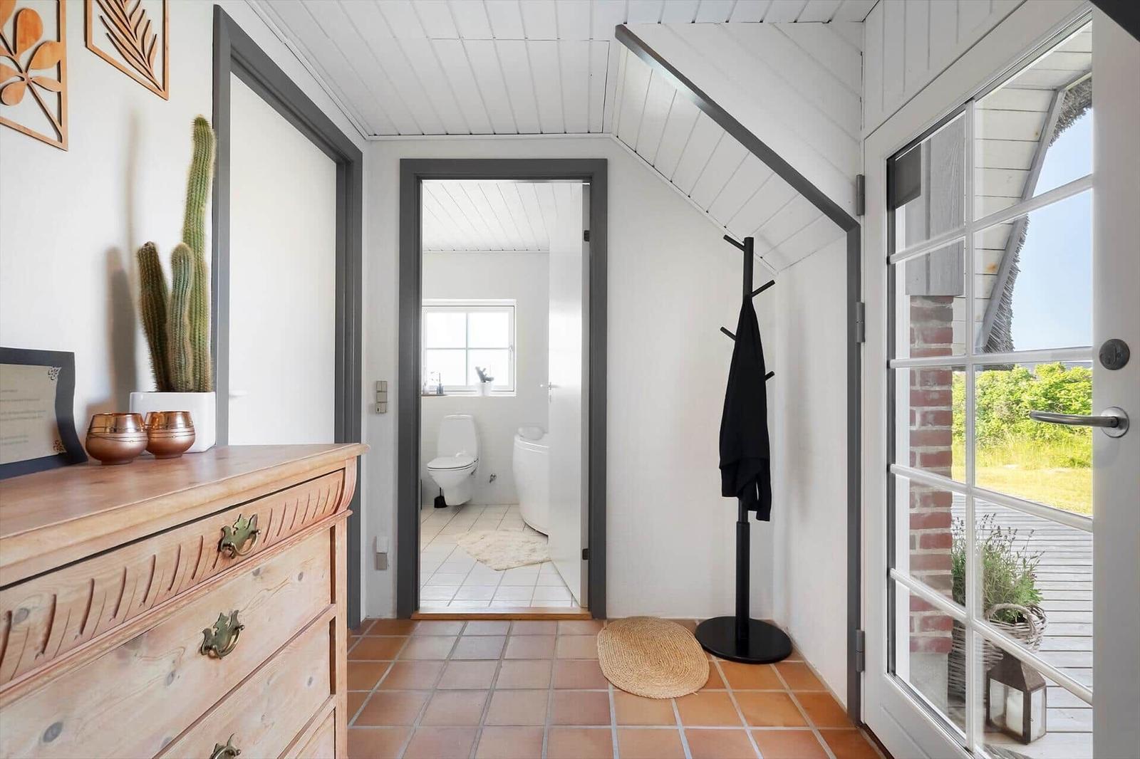 Eingangsbereich mit Schrank, Kleiderständer und Blick in die Toilette.