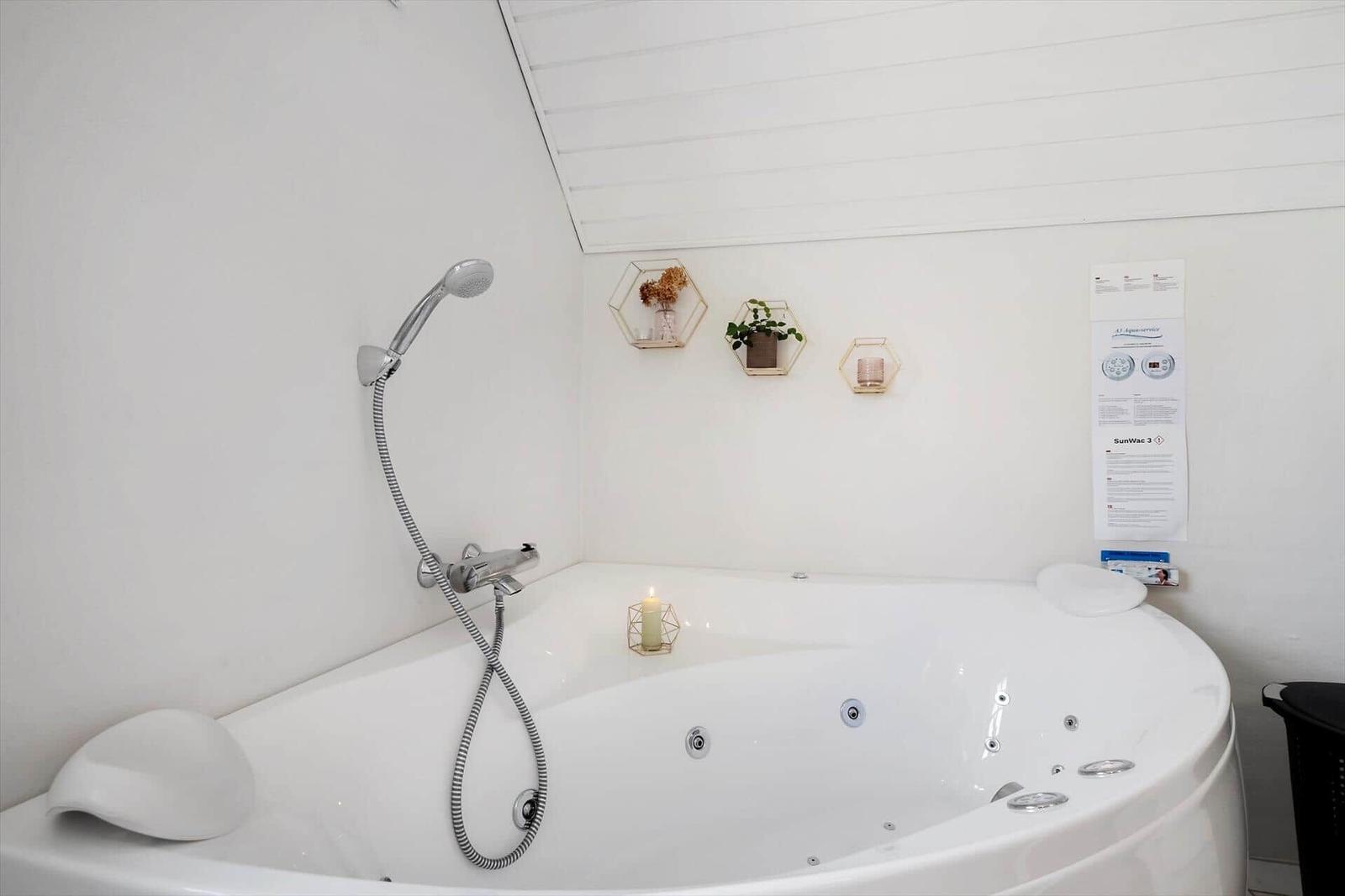 Eine weiße Whirlpool-Badewanne mit Duschkopf und dekorativen Wandhaltern.