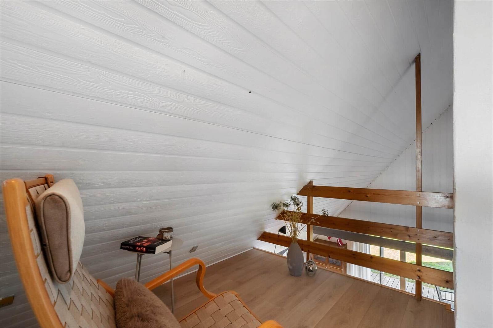 Raum mit Holzdecke, Sessel und Treppe zur Galerie