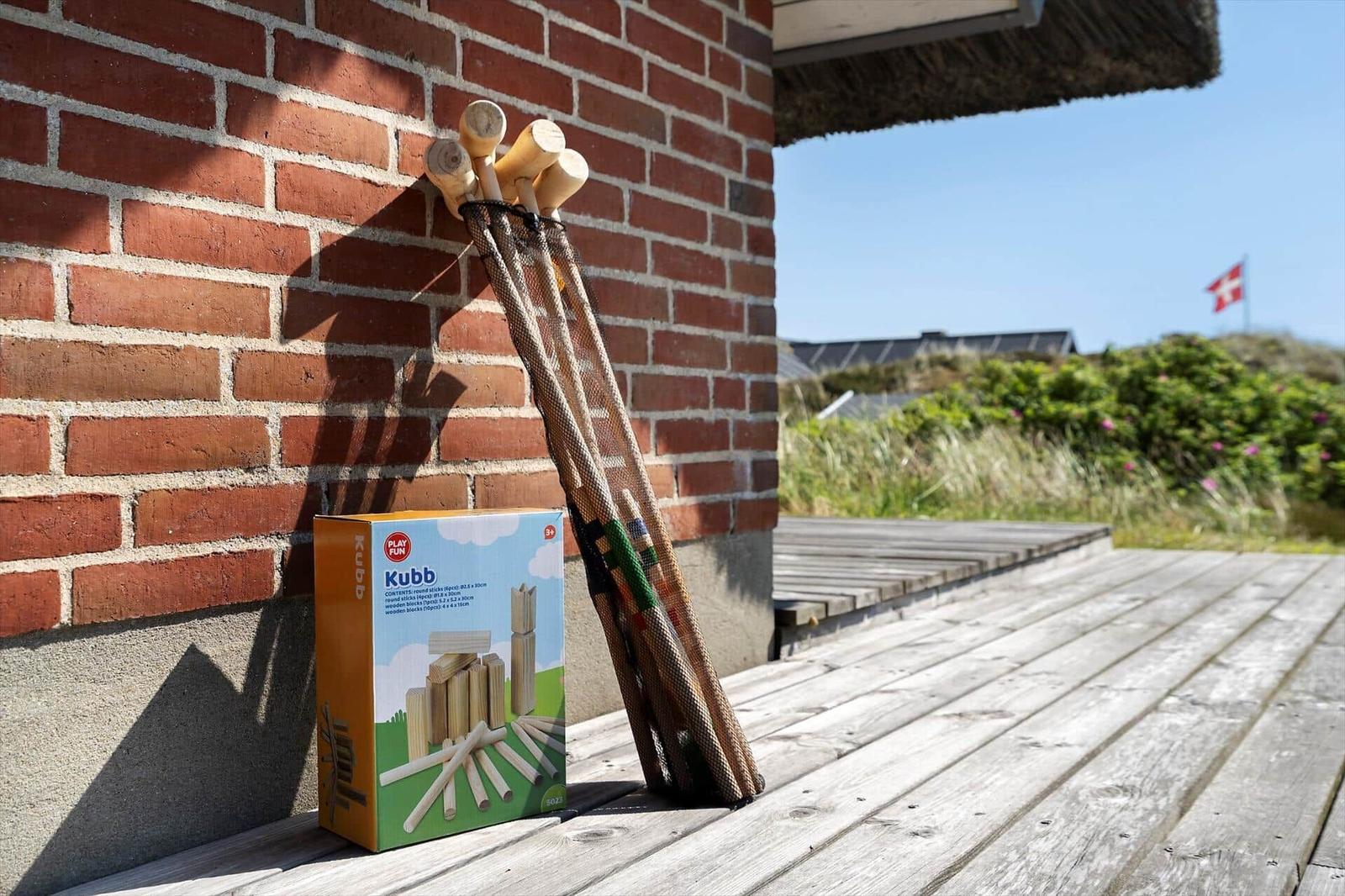 Kubb-Spielzeug auf Terrasse neben Backsteinwand und Dach