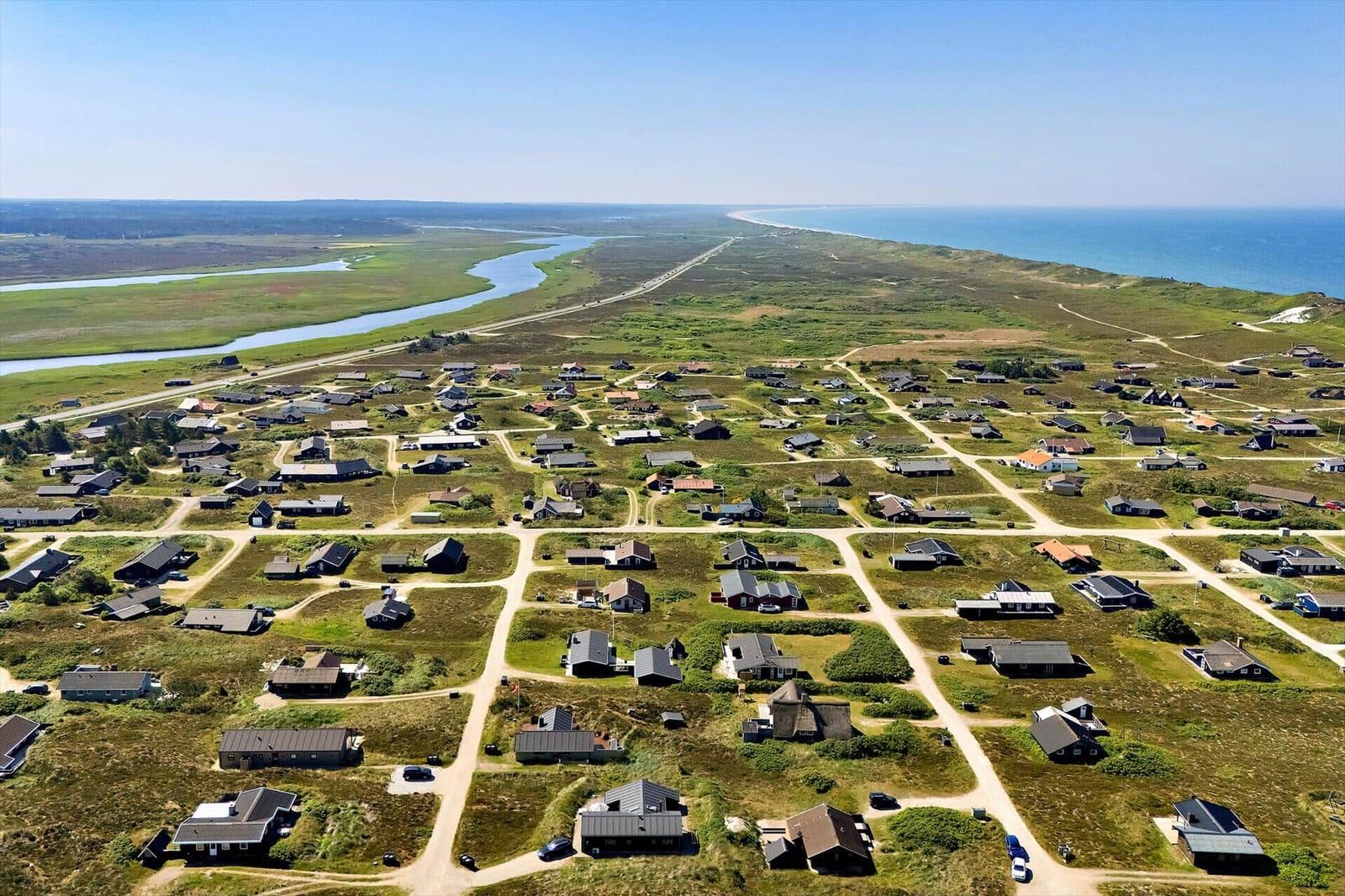 Aerielansicht von Häusern entlang einer Küstenstraße mit Fluss und Meer im Hintergrund.