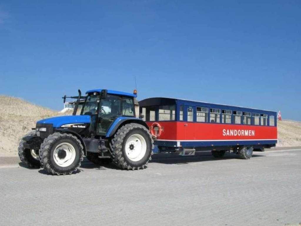 Blauer Traktor zieht einen roten und blauen Wagen mit der Aufschrift SANDORMEN.