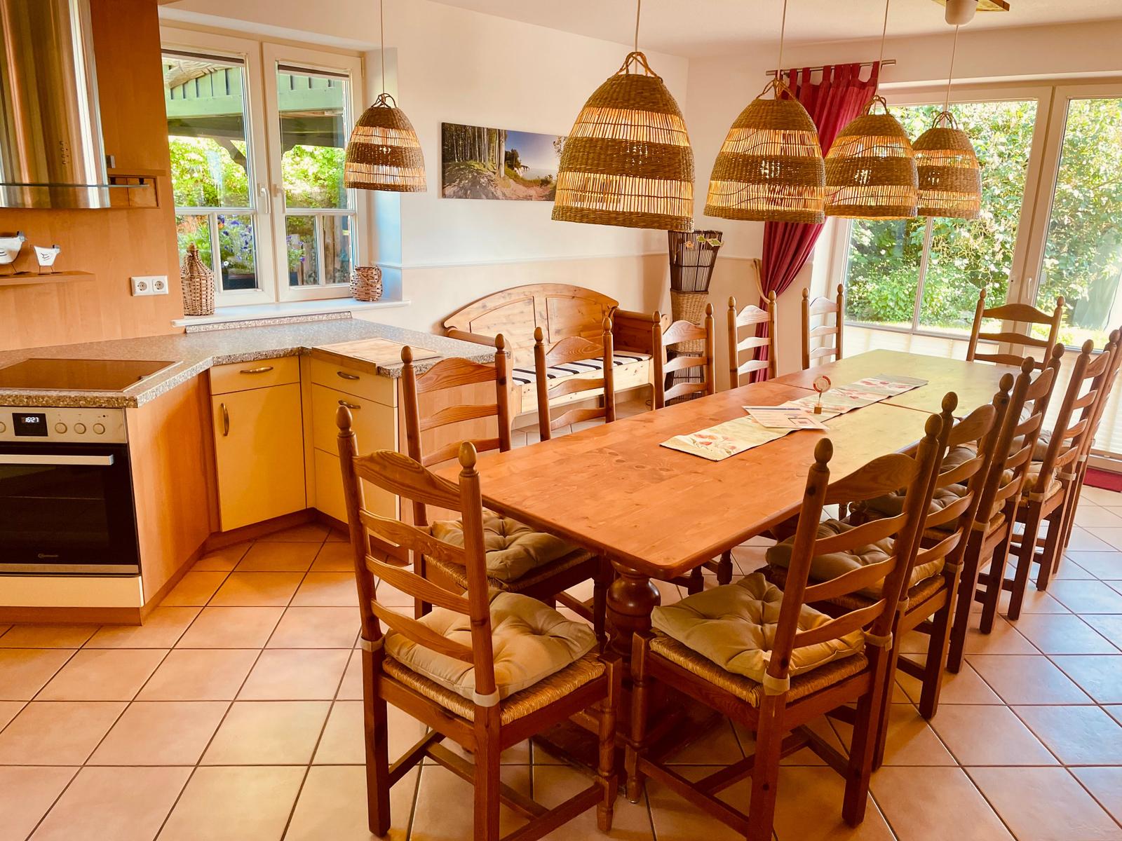 Küche mit Essbereich, Holztisch, Stühle und hängende Lampen.