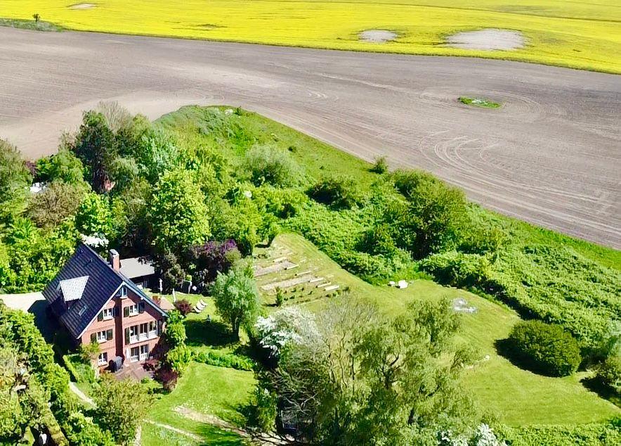 Haus mit Garten und Blick auf Felder mit Rapsblüten.