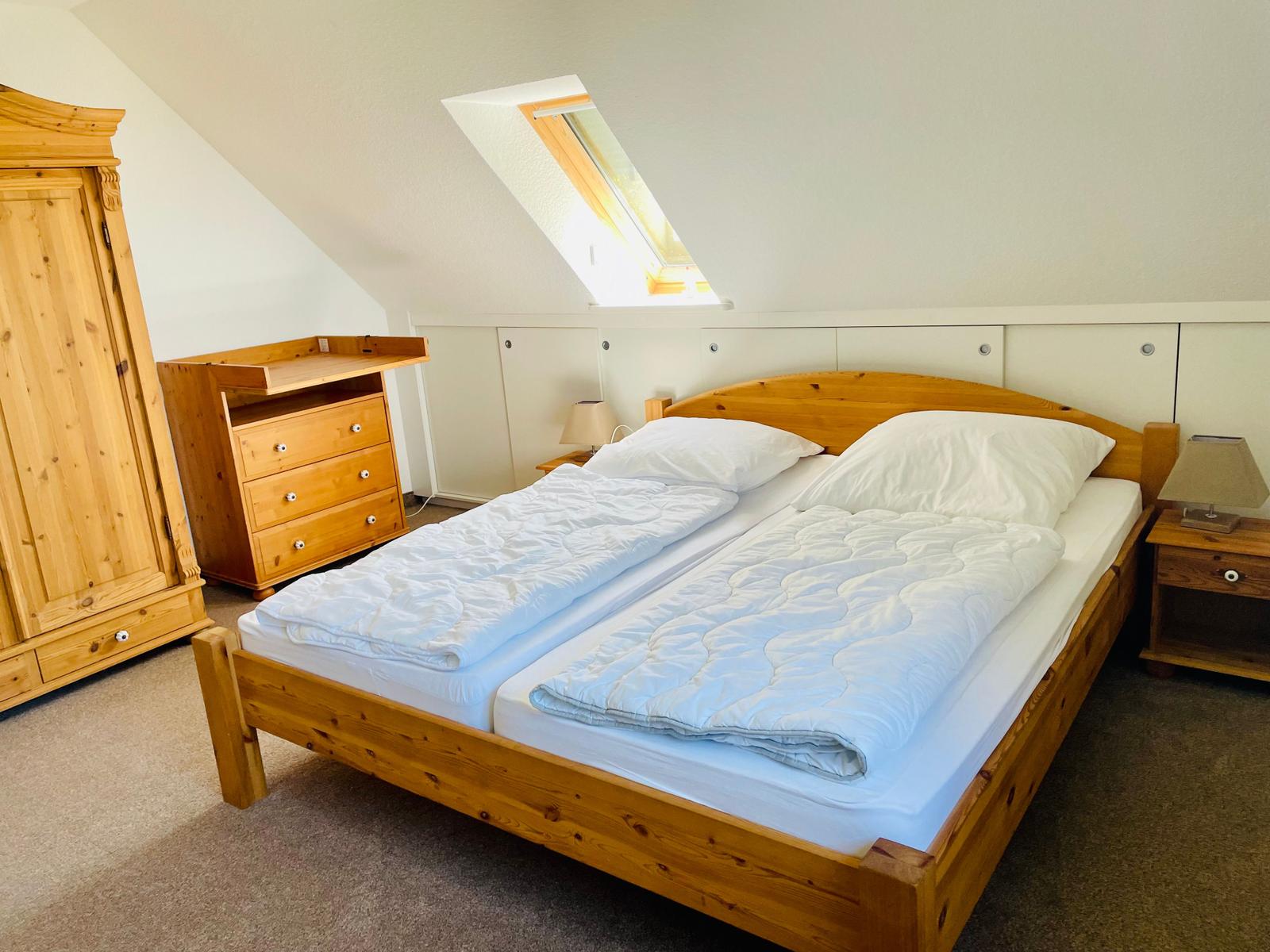 Schlafzimmer mit Doppelbett, Holzmöbel und Dachfenster.