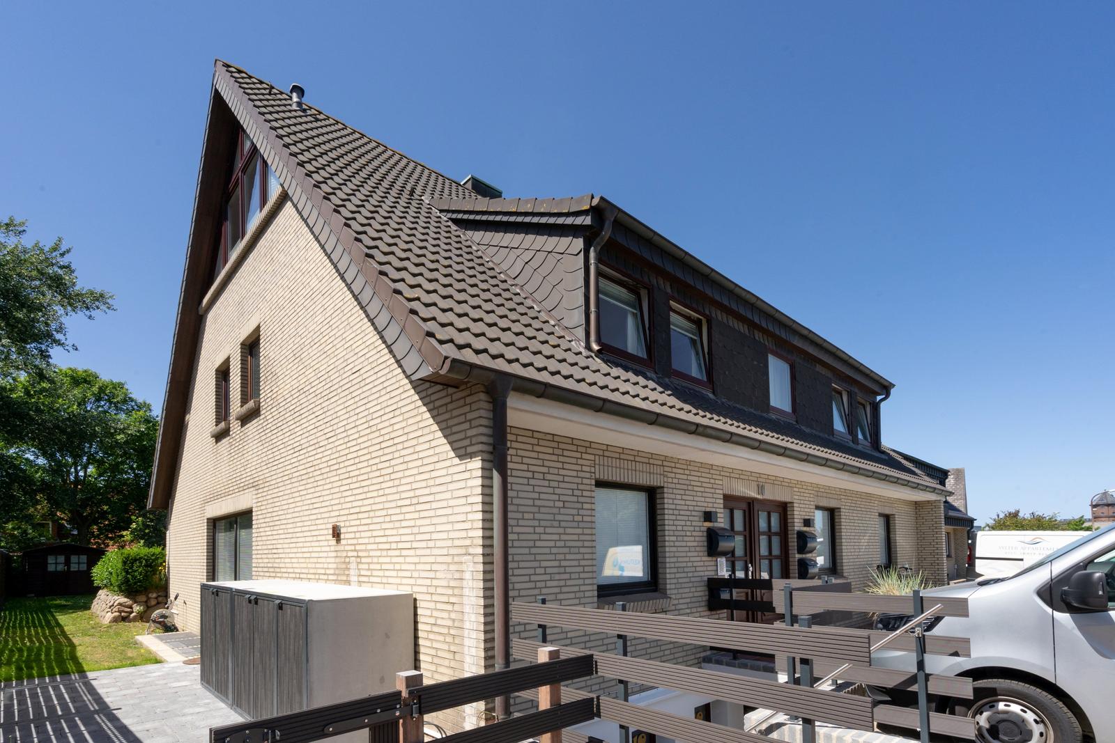 Moderne Villa mit Terrasse und Garten. Dunkelbraunes Dach und hellbeige Fassade.