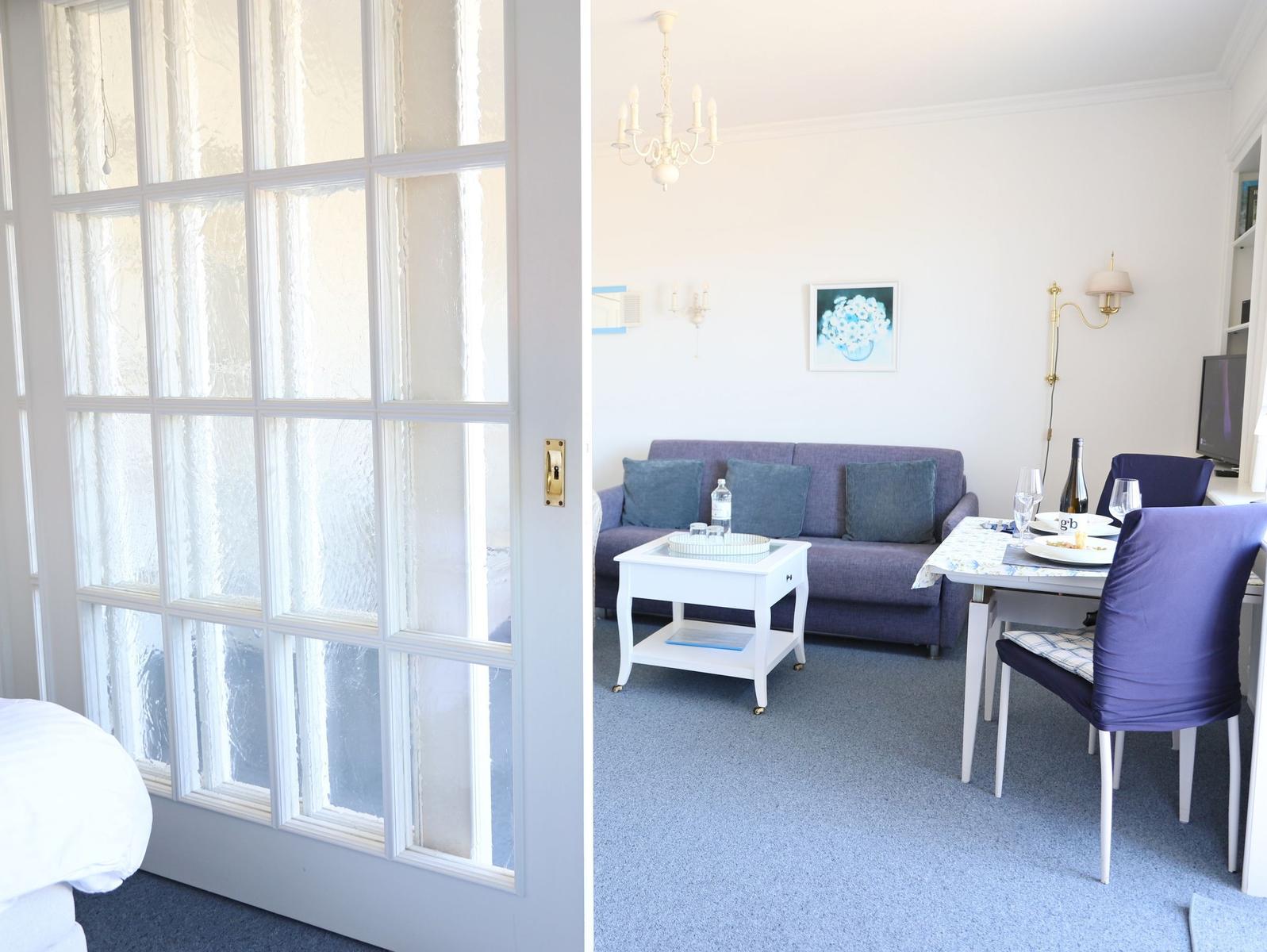 Ein Raum mit Sofa, Esstisch und Fenster mit getöntem Glas.