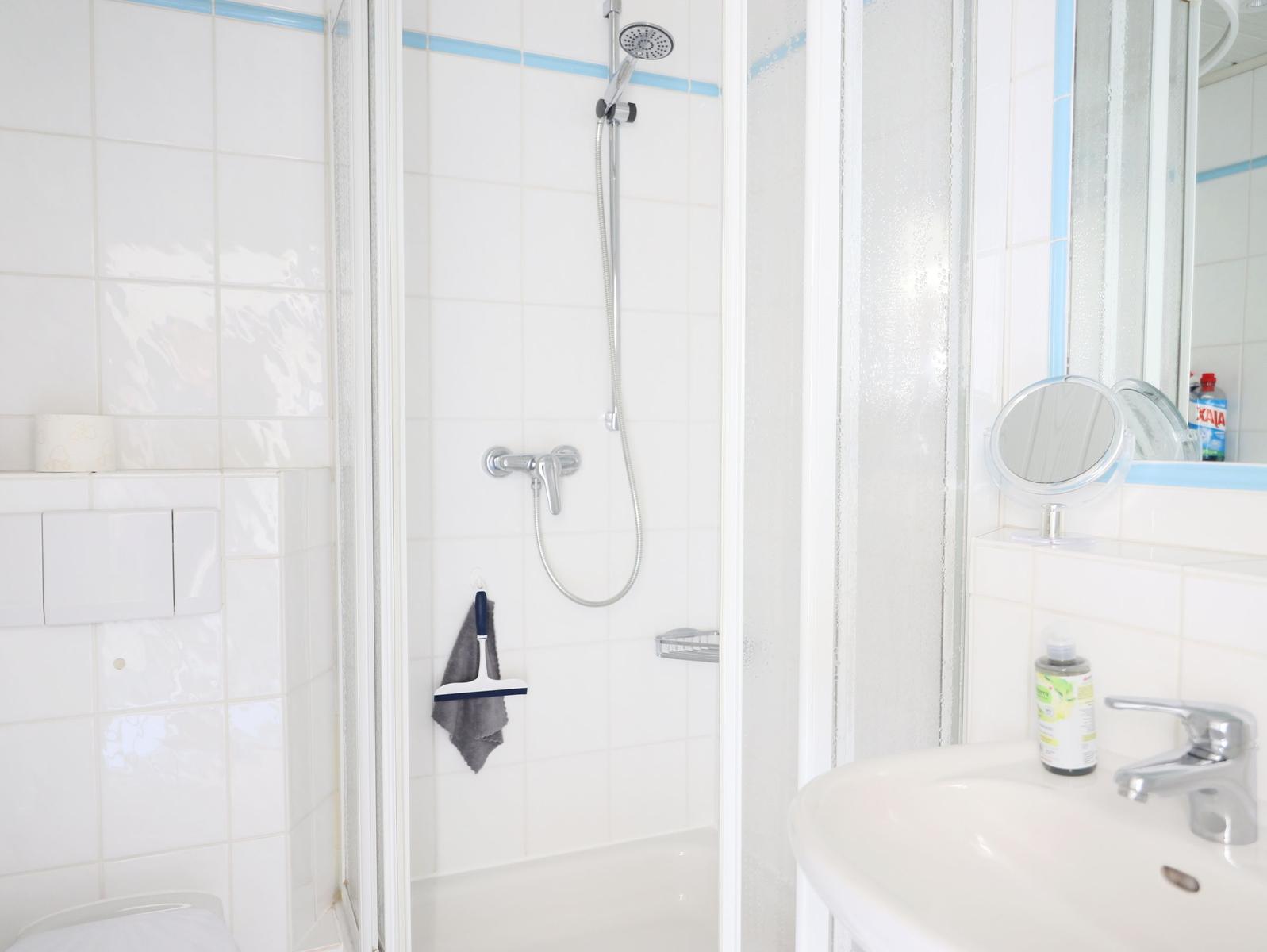 Badezimmer mit Dusche, Waschbecken und Spiegel