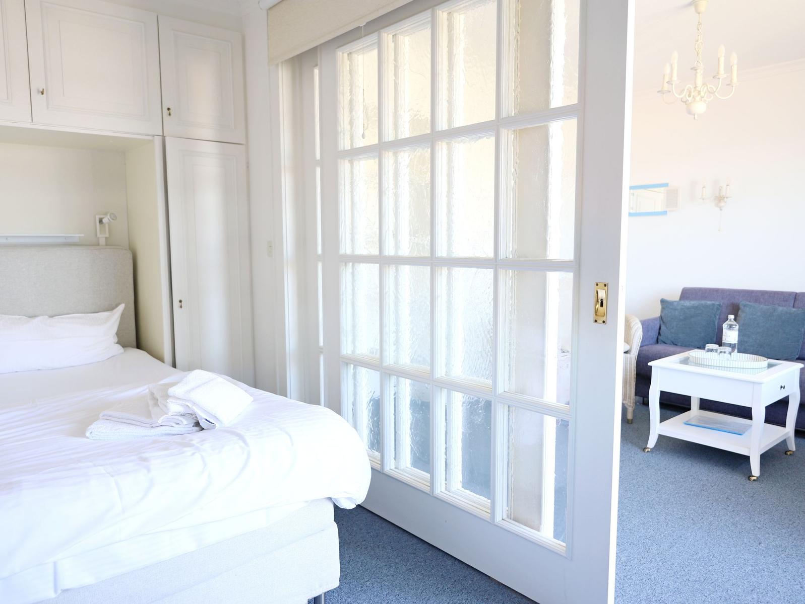 Schlafzimmer mit Bett und Kleiderschrank. Durchgehende Glaswand trennt Raum vom Wohnbereich.