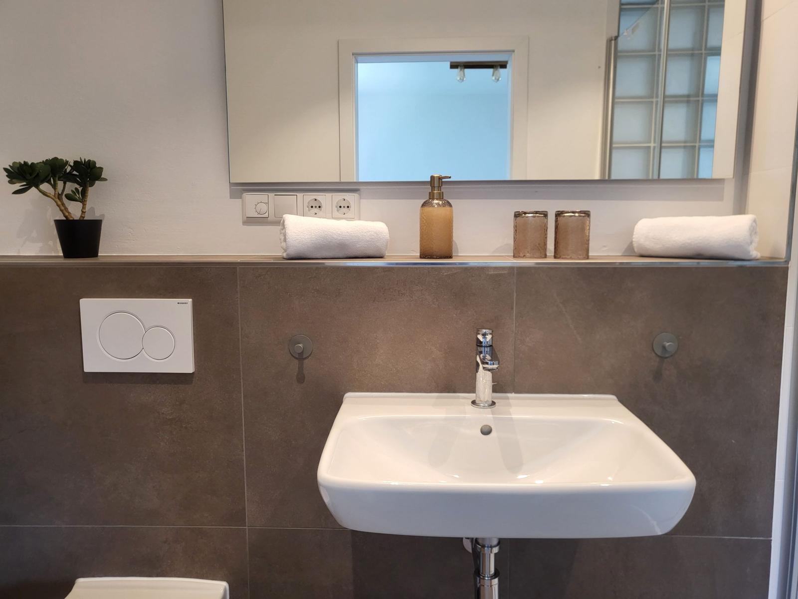 Badezimmer mit Waschbecken, Spiegel und Handtüchern