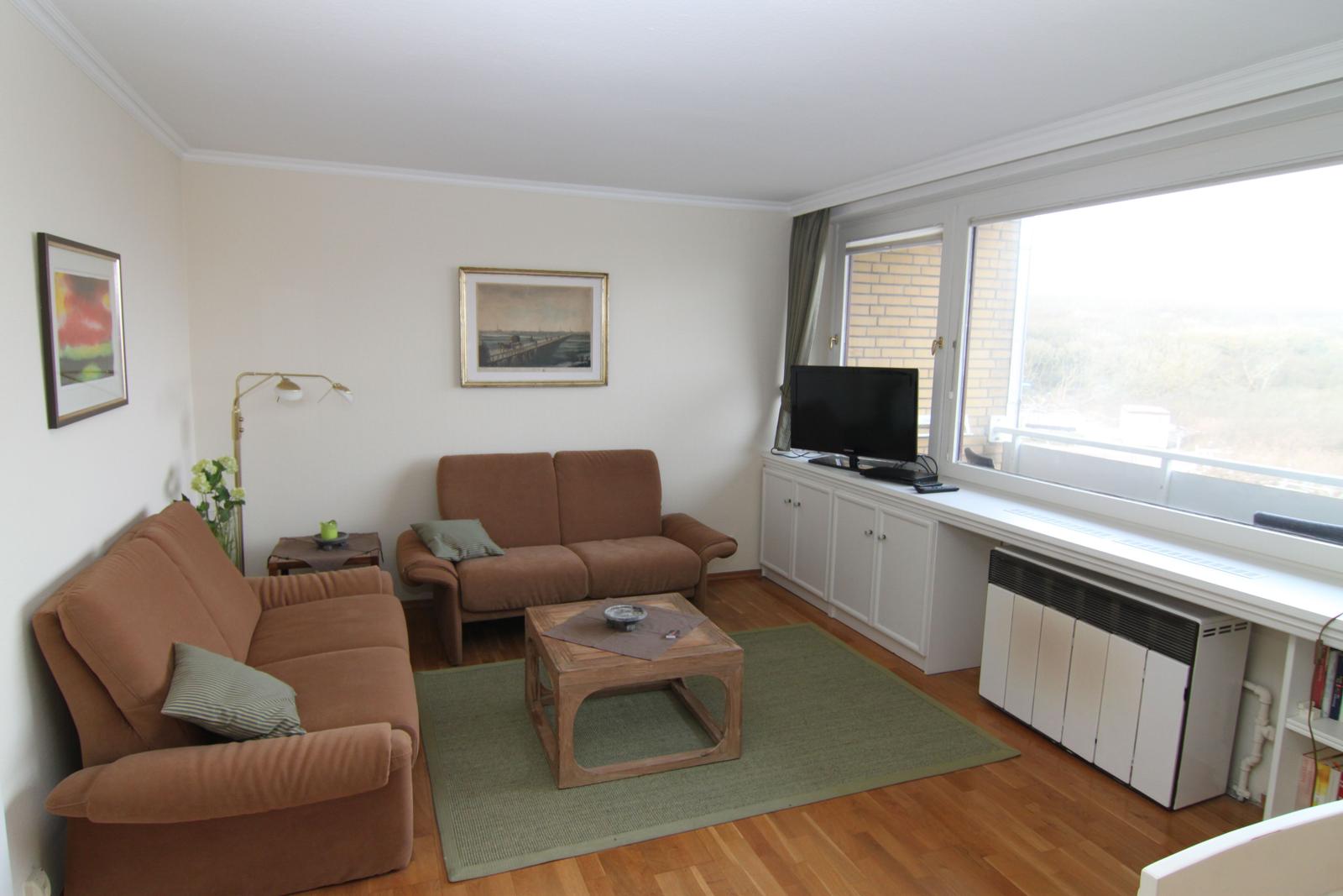 Wohnzimmer mit zwei braunen Sofas, Holzfußboden und großem Fenster.