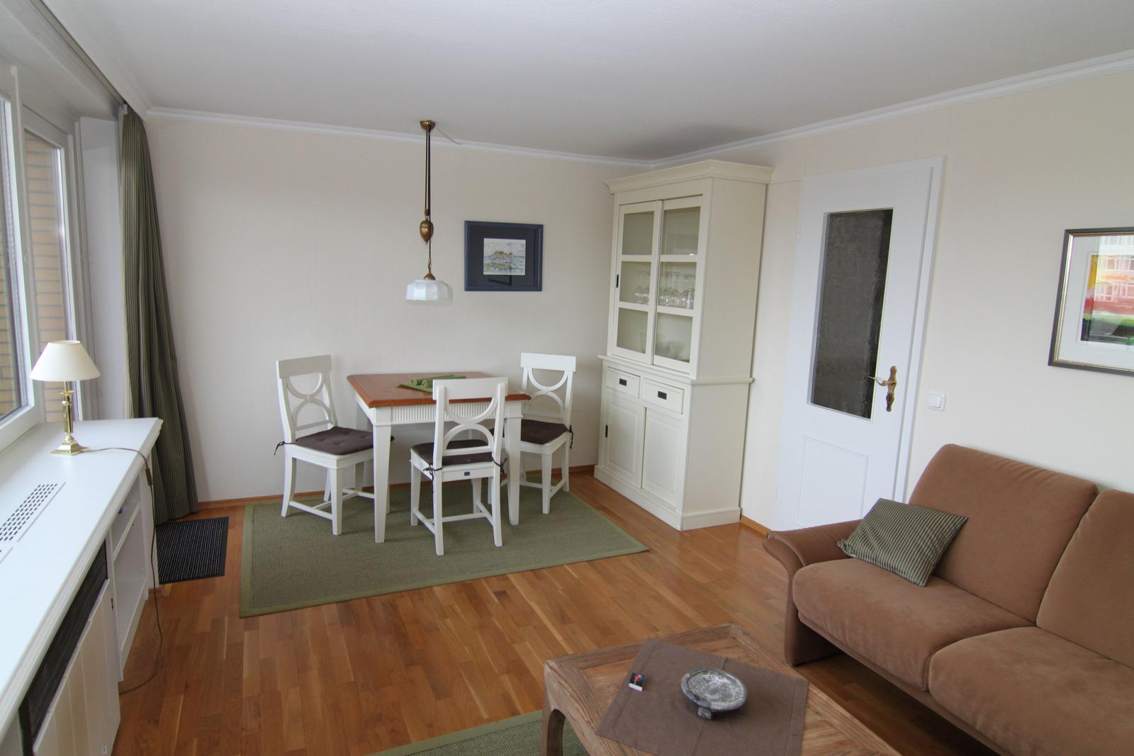 Wohn- und Essbereich mit Sofa, Tisch, Stühlen und Sideboard.