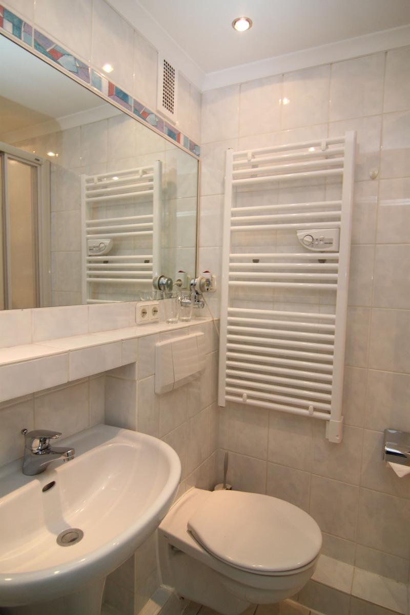 Badezimmer mit Waschbecken, Toilette und Heizkörper